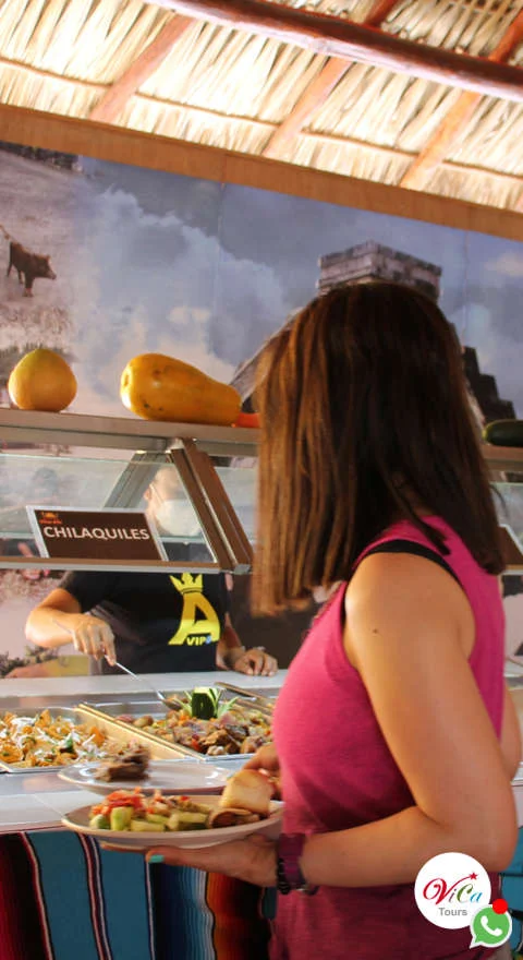 Turista sirviéndose platillos de la comida buffet incluido en el tour Chichén Itzá desde Costa y Playa Mujeres