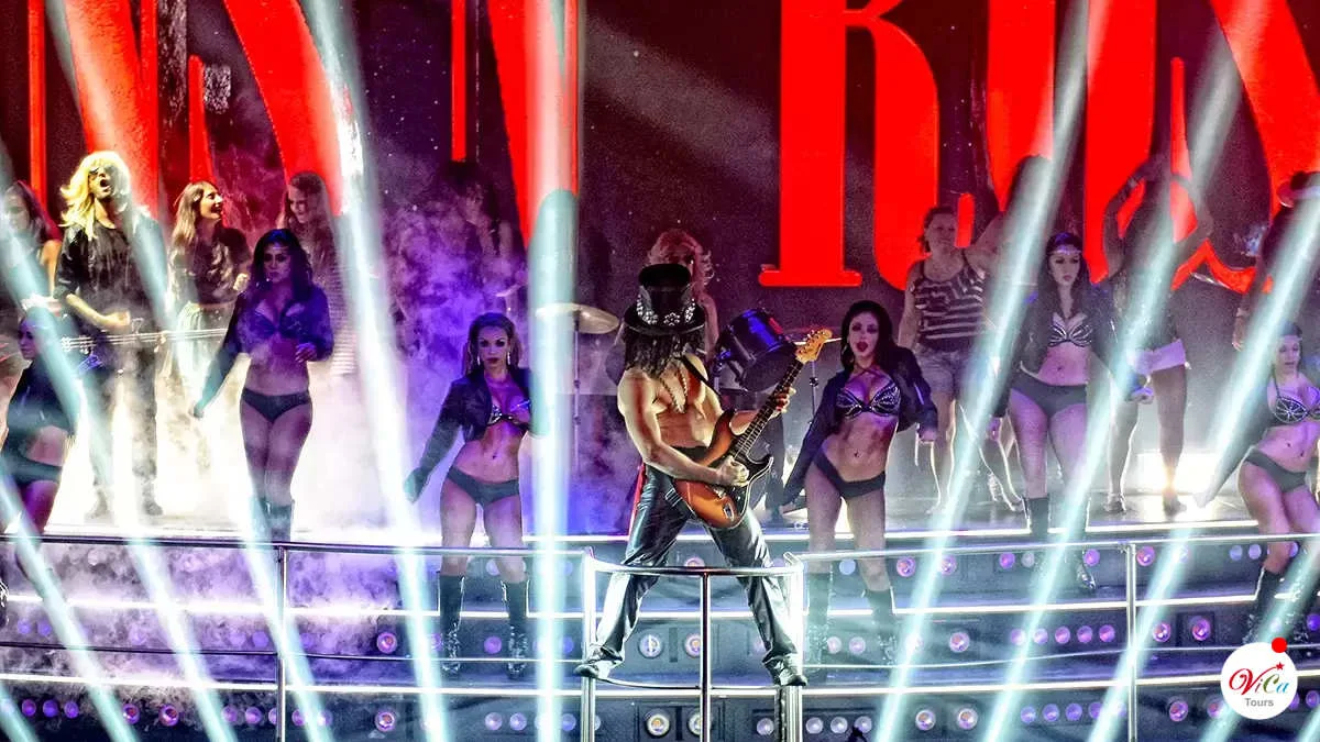 Bailarines y guitarrista recreando un show de rock clásico en el escenario de Coco Bongo Cancún